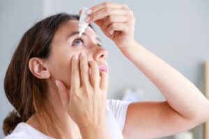 A woman putting Upneeq eye drops in her eyes