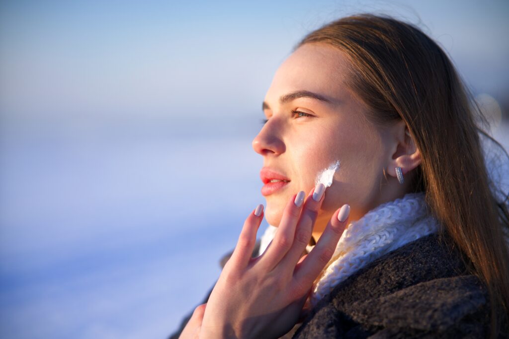 Woman in cool winter weather applying skincare for dry skin in Lone Tree