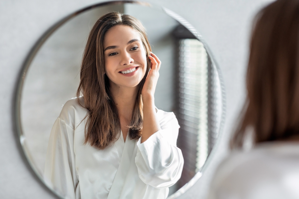 Portrait of beautiful woman looking in the mirror admiring her beautiful complexion.