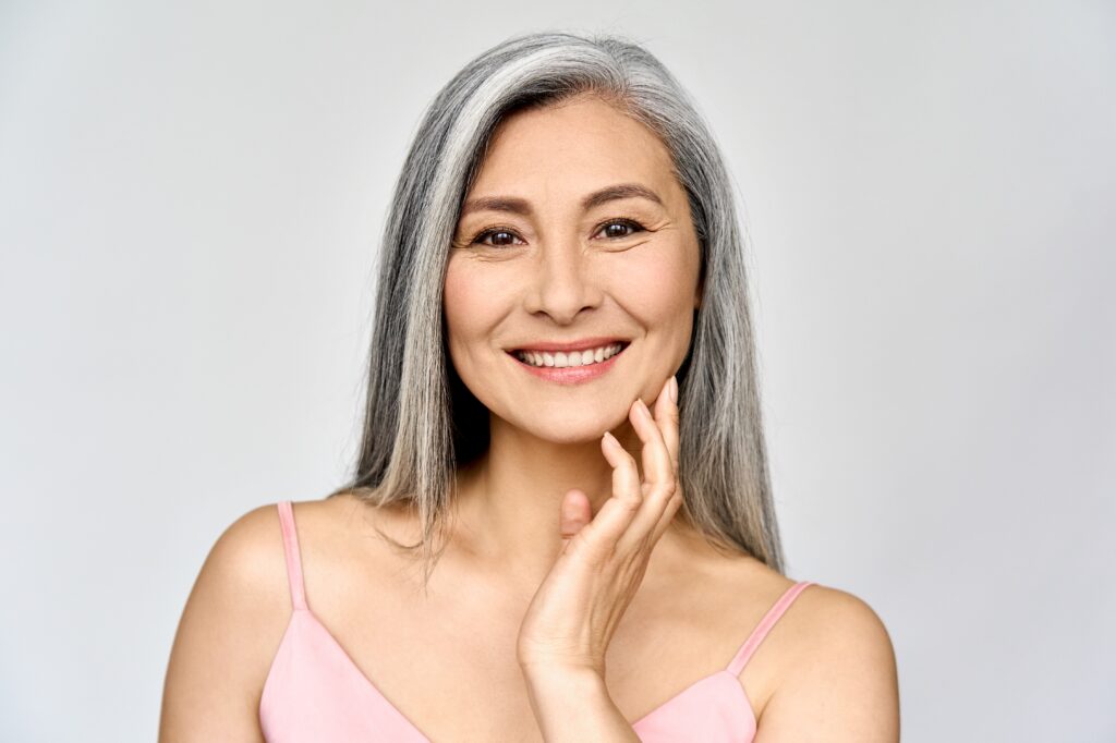 Mature woman in pink cami smiling with glowing skin after a VI chemical peel