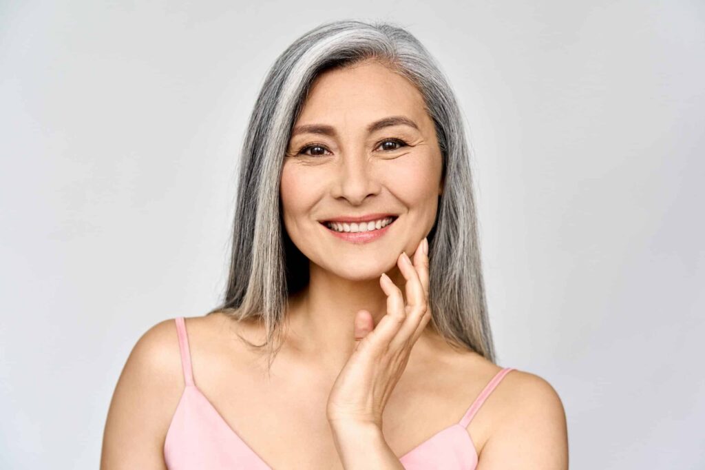 Mature woman in pink cami smiling with glowing skin after a VI chemical peel