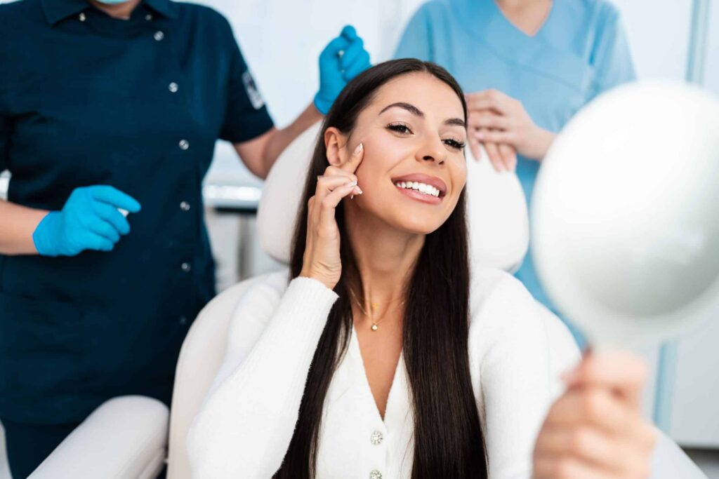 Woman look at her results after getting injectable treatment, with providers behind her