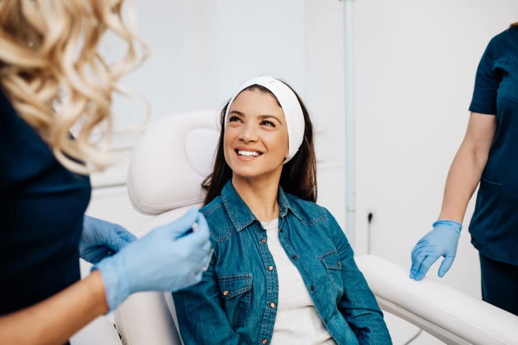 Facial aesthetics surgery treatment Smiling woman preparing for aesthetic treatment with providers.