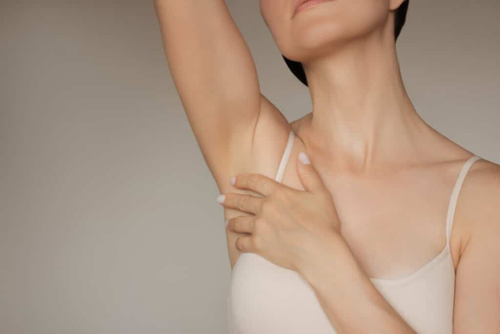 Woman touching her underarm, illustrating excessive underarm sweating and BOTOX treatment for hyperhidrosis.