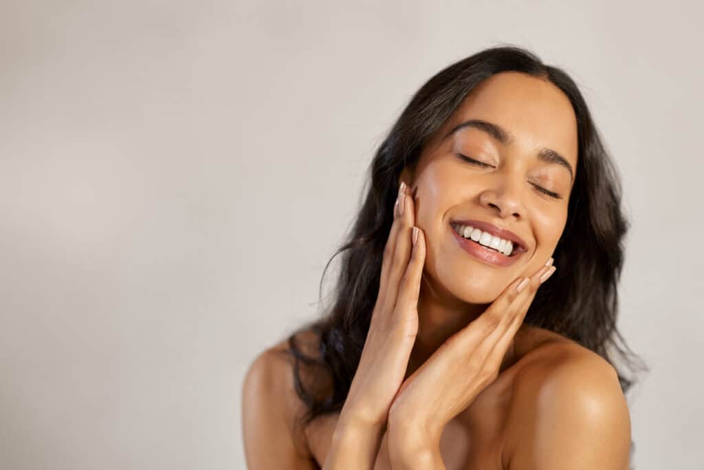 Woman touching her smooth facial skin, illustrating skin rejuvenation with Morpheus8 or Procell MicroChanneling.